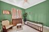 Room featuring high ceilings, large-format tile flooring, crown molding, and a central ceiling fan