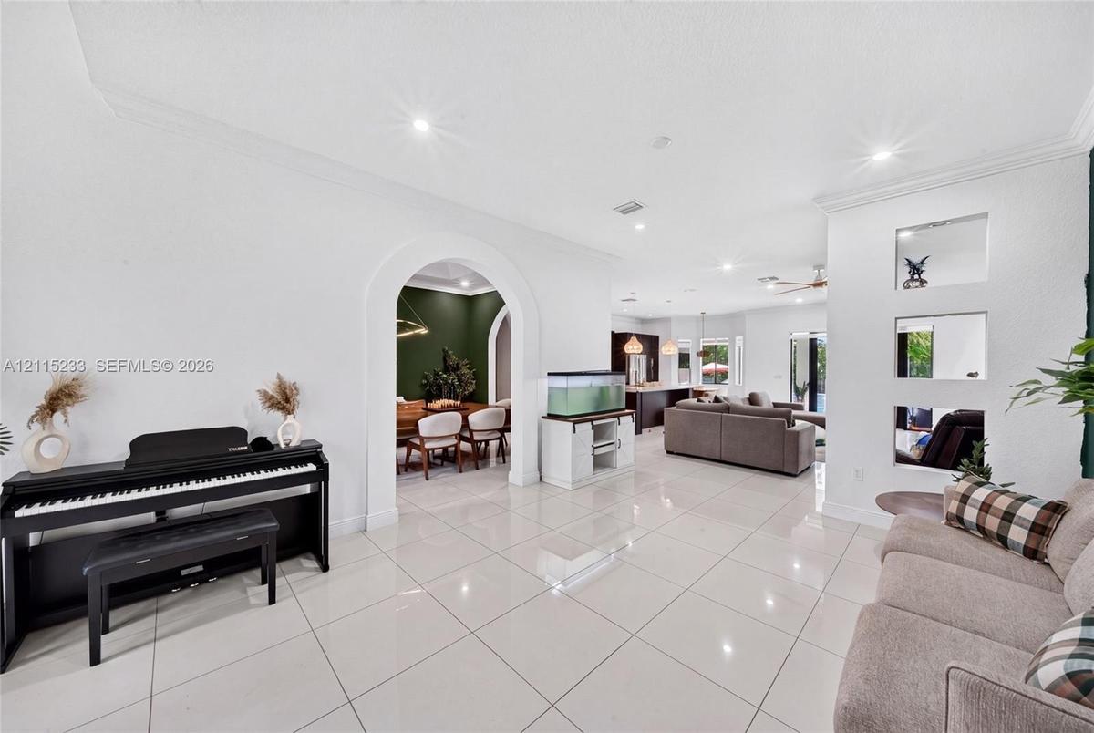 Polished tile flooring, crown molding, recessed lighting, and a decorative arched entryway featuring recessed wall niches