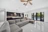 Open-concept kitchen featuring dark cabinetry, expansive kitchen island with a neutral countertop, large-format tile flooring, recessed lighting, and 