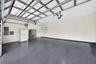 Multi-car garage featuring epoxy-coated flooring, built-in wall shelving, and mounted electric door openers