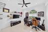 Interior room featuring large-format ceramic tile flooring, arched window with integrated blinds, and a multi-blade ceiling fan with centered light fi
