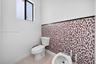 Decorative mosaic tile wainscoting, porcelain floor tiling, white vitreous china toilet, and bidet with metallic hardware