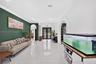 Expansive interior featuring oversized white floor tiles, a deep green accent wall, arched doorways, and a double-door entrance with a semicircular tr