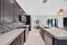 Kitchen featuring dark cabinetry, expansive light-toned solid surface countertops, a mosaic tile backsplash, stainless steel appliances, and large-for