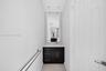 Dark wood-finish cabinetry, solid surface countertop, rectangular undermount sink, full-height wall mirror, and chrome fixtures