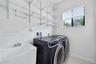 Laundry room featuring white utility sink with chrome faucet, tiered wall-mounted wire shelving, and neutral tile flooring