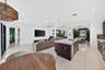 Open-concept living space featuring large-format tile flooring, a kitchen island with stone-surface countertop, recessed lighting, decorative woven pe