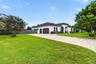 Stucco exterior featuring an arched entryway, decorative corbels, a multi-car garage with arched doors, and a paver driveway