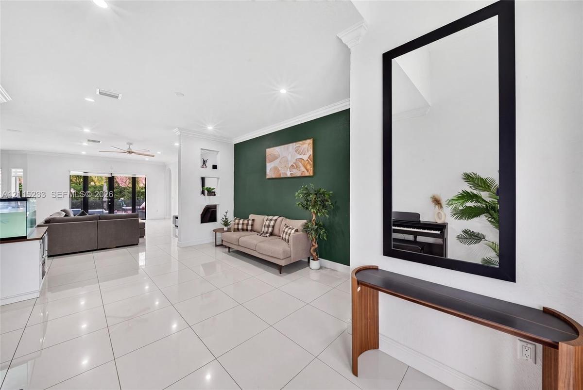 Polished tile flooring, recessed ceiling lighting, crown molding, a dark-toned accent wall, and built-in wall niches