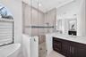 Freestanding soaking tub, walk-in shower with glass enclosure, mosaic tile wall accents, dark-finish wood cabinetry, and large-format wall mirror