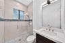 Bathroom featuring a vanity with a light-toned countertop, a frameless glass shower enclosure, a shower with stone-tile flooring and a decorative mosa
