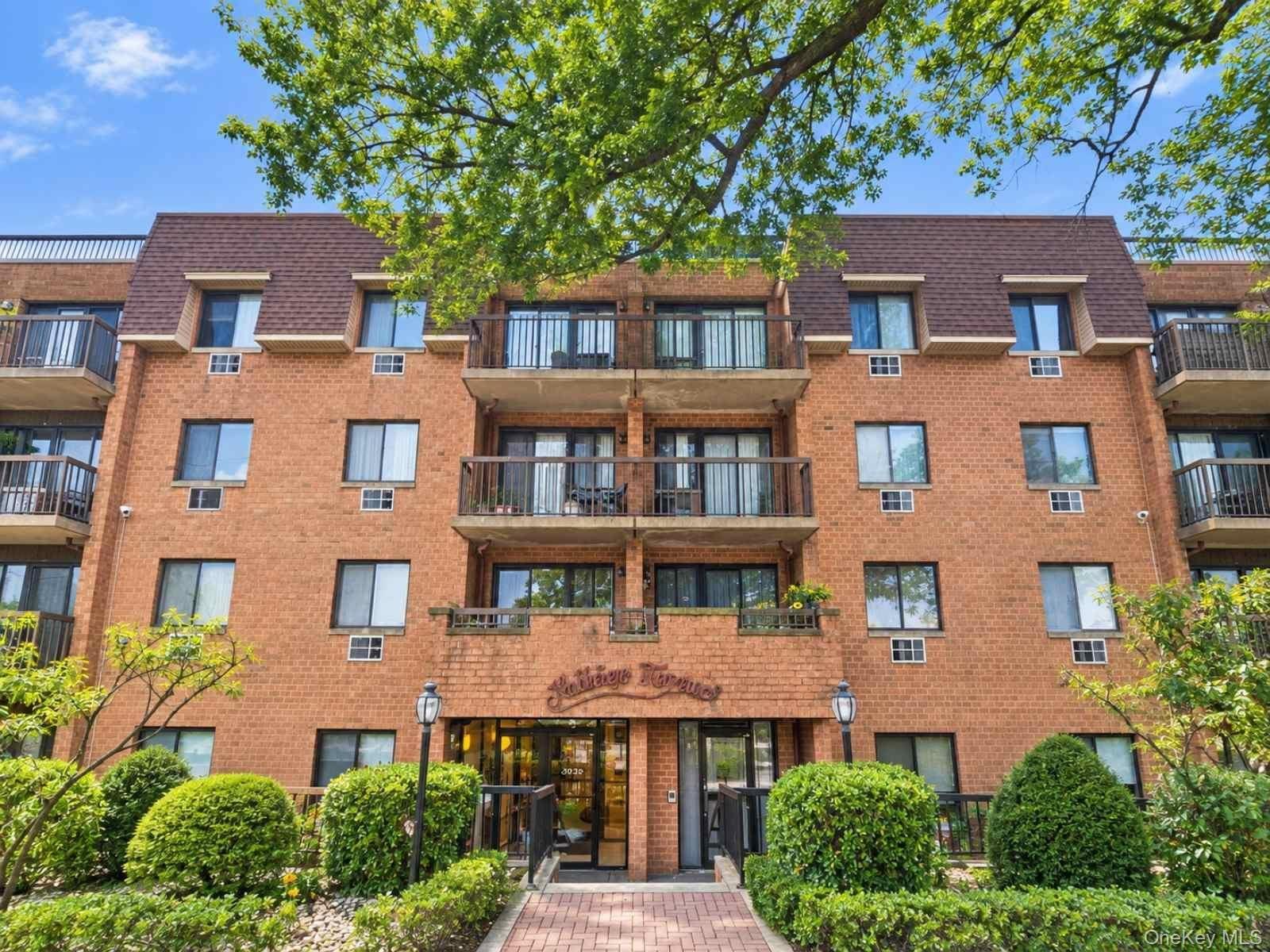 Brick exterior building with multiple private balconies, a mansard roof, and an inviting entryway with a paved walkway