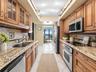Kitchen includes abundant wood cabinetry, stone counters and backsplash, stainless appliances and extensive preparation space.