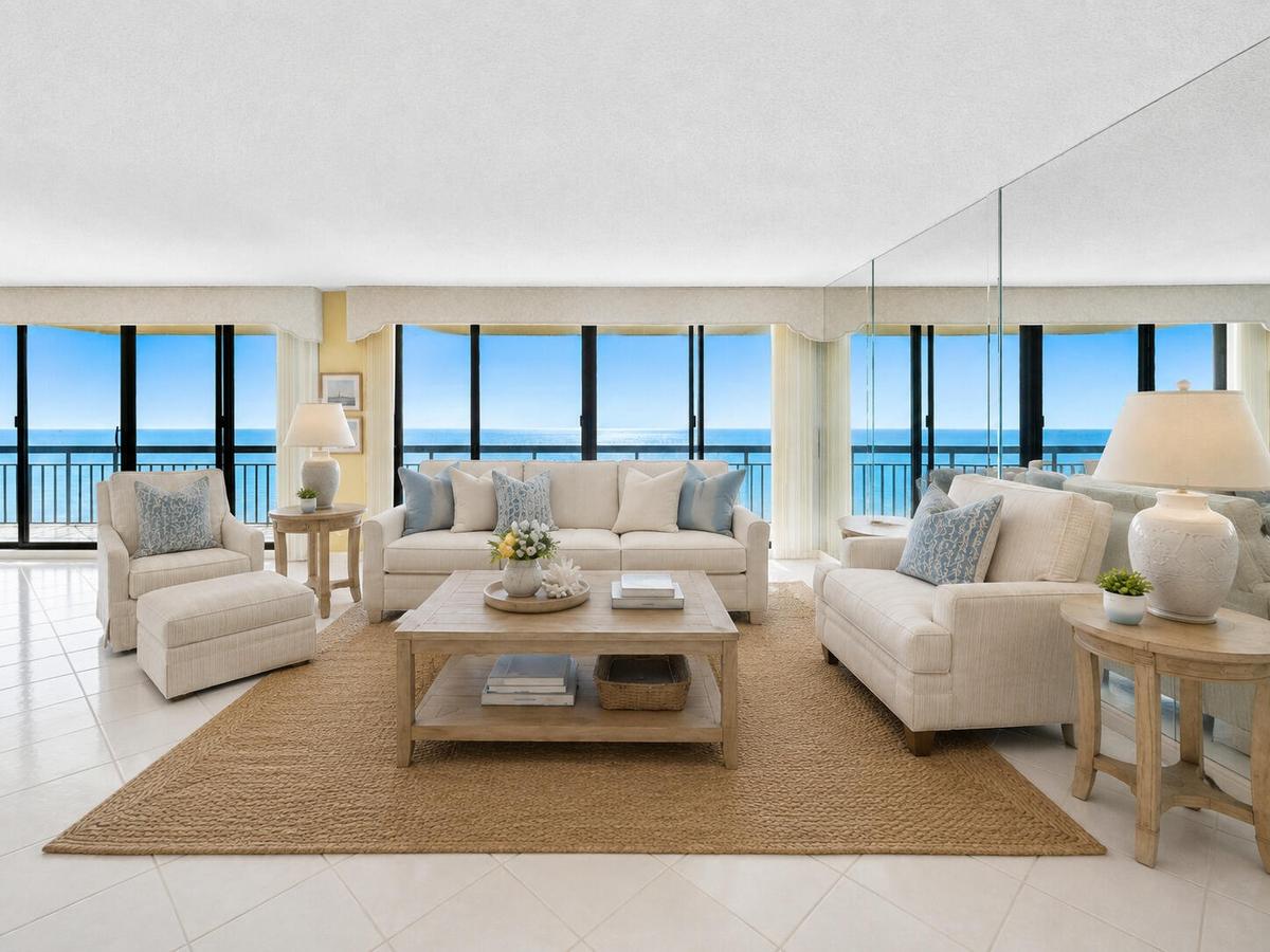 Walls of glass frame direct Atlantic views from the expansive living room. Virtually staged; furnishings and décor are digitally added and are not inc