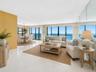 Two walls of glass frame direct ocean views from the expansive living room. Virtually staged; furnishings and décor are digitally added and are not in