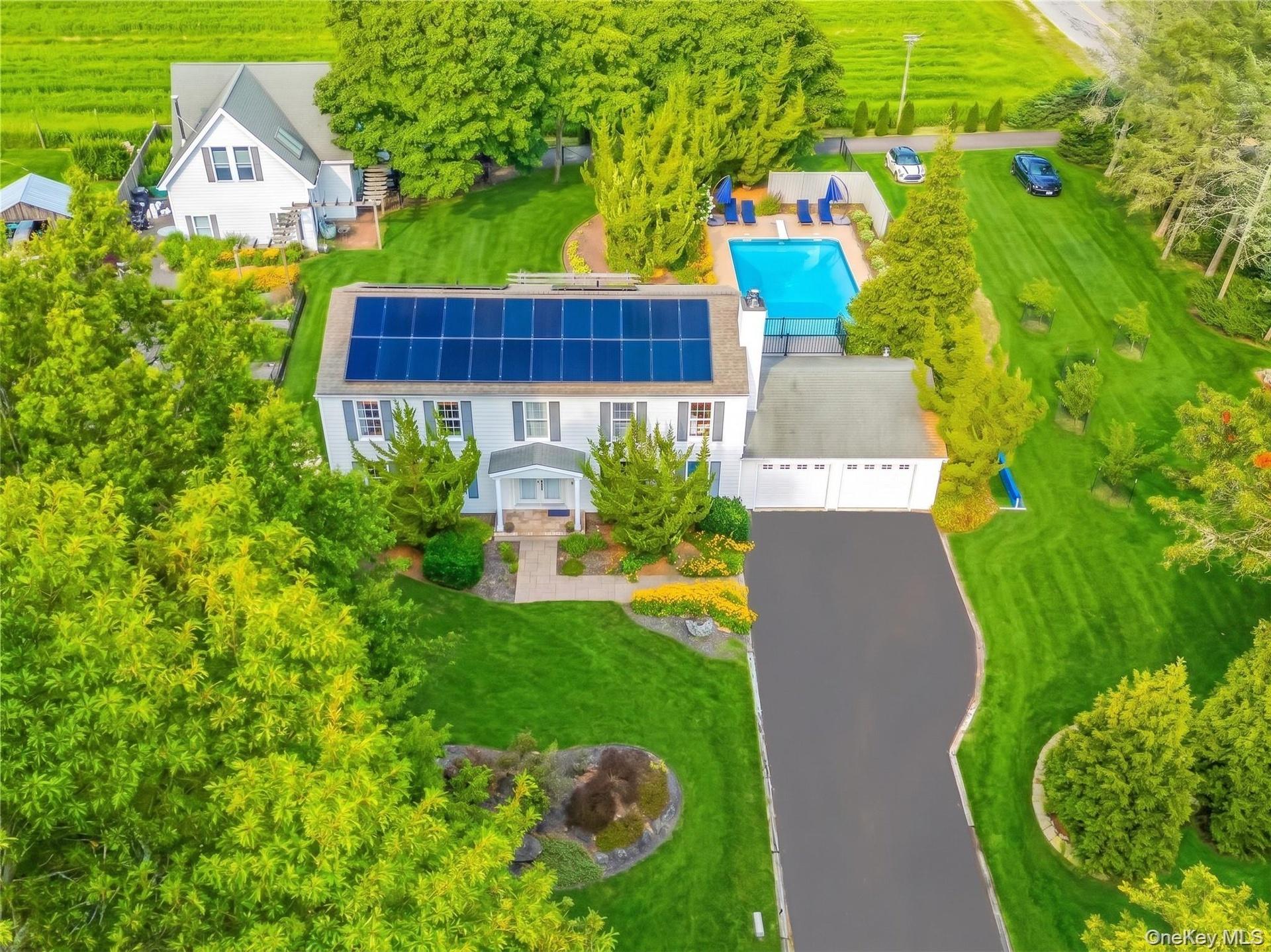 Aerial view: guest house and pool with lush surroundings.
