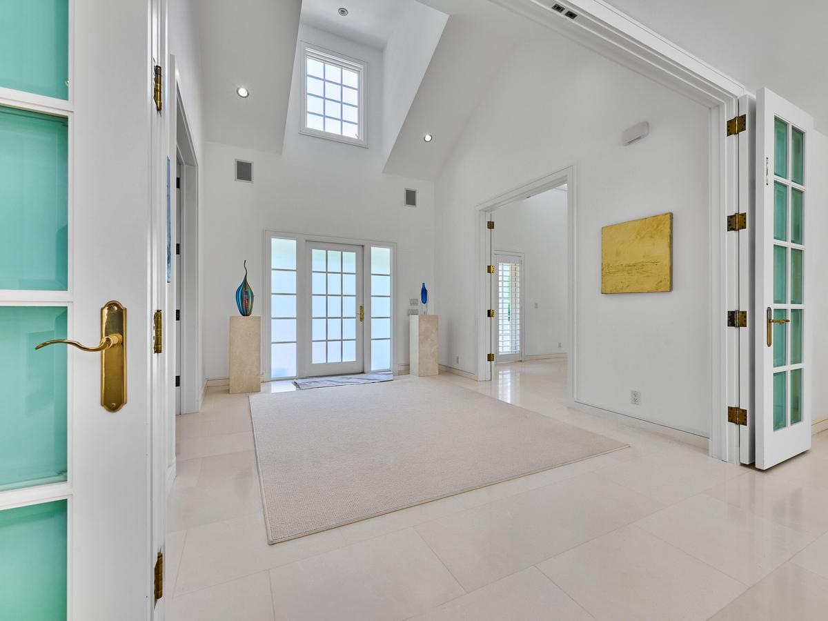 Soaring ceilings and striking architectural volume, create a sophisticated transition from the home's classic Coastal Colonial exterior to its bright,