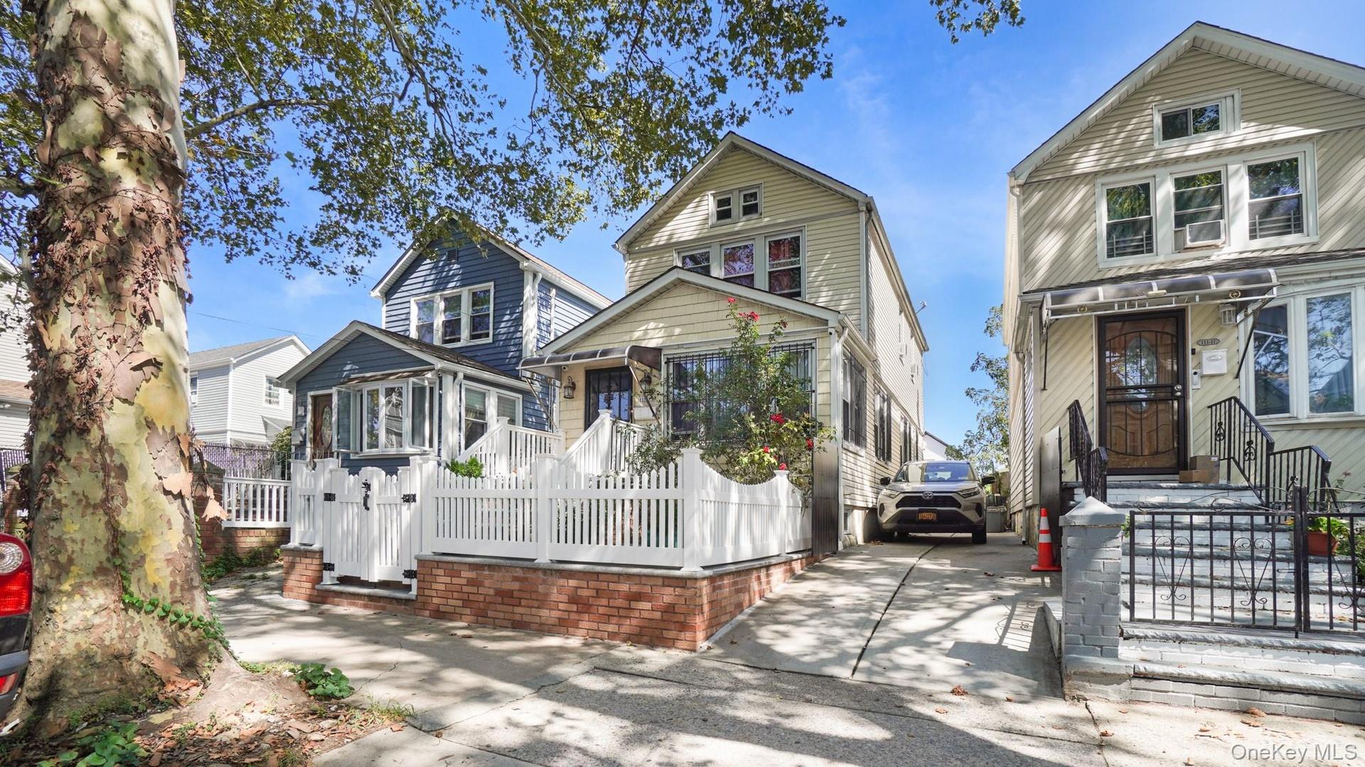 Picket fence with brick base, sunroom, and private driveway