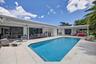 Enjoy relaxing in your beautiful private pool looking toward outdoor kitchen, dining and living