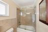 Primary En-Suite Bathoom with Custom Cabinet, Granite Countertop, Bathtub & Shower Combination with Glass Enclosure all behing a Frosted Glass Bathroo