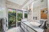 Bright, sophisticated primary bathroom with serene garden views, creating a fresh and relaxing atmosphere.