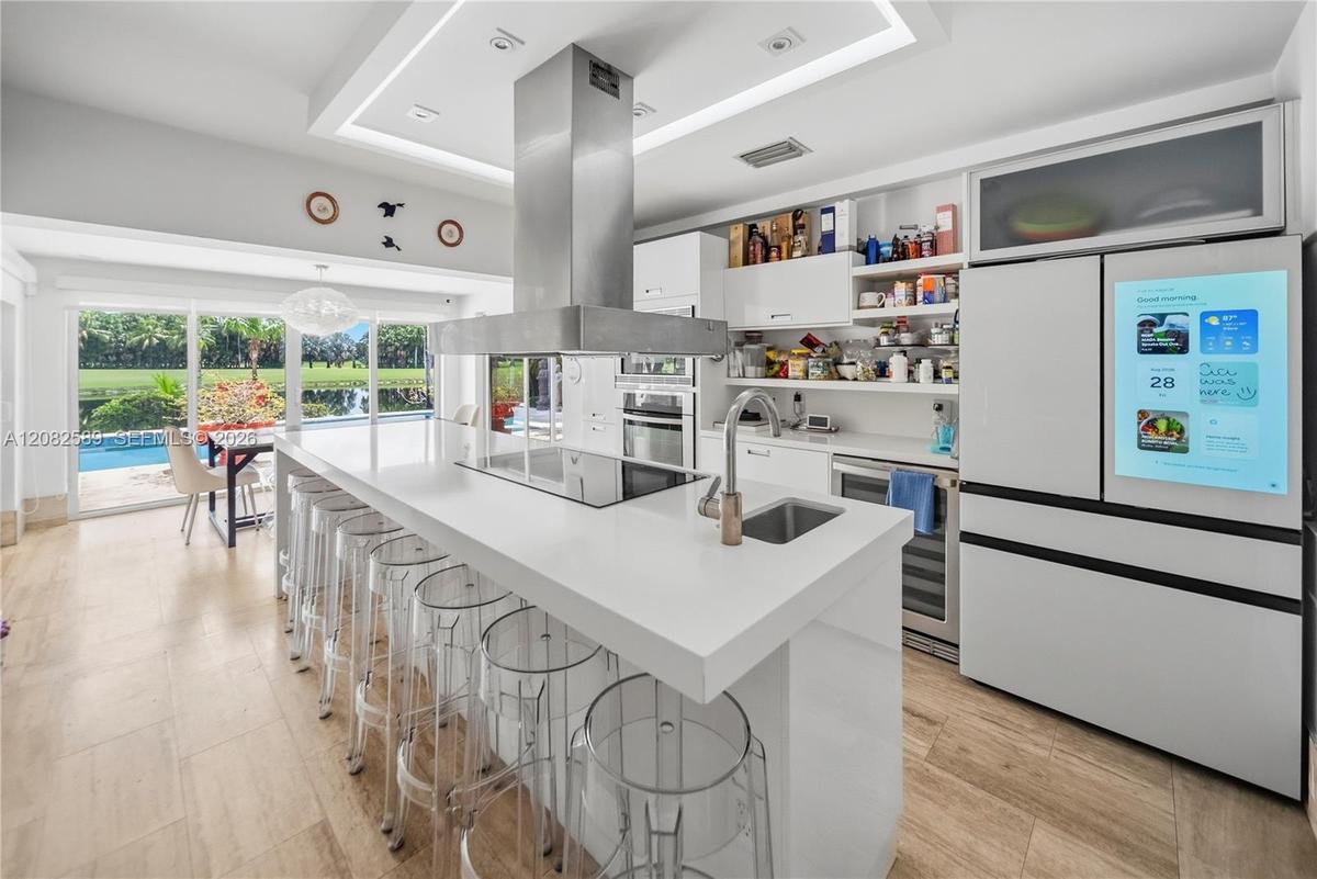 Stunning contemporary kitchen featuring an expansive island, sleek finishes, and beautiful views of the pool and lush greenery.
