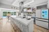 Stunning contemporary kitchen featuring an expansive island, sleek finishes, and beautiful views of the pool and lush greenery.