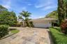 Spacious stone-paved driveway with an attached two-car garage, surrounded by lush tropical landscaping.