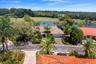 Aerial view showcasing the home’s lush tropical setting with beautiful lake and golf course views.