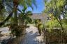 Tropical garden walkway framed by lush greenery and natural stone accents, creating a serene and inviting approach to the home.
