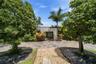 Beautifully landscaped front approach framed by mature tropical greenery, offering a private and inviting entrance.