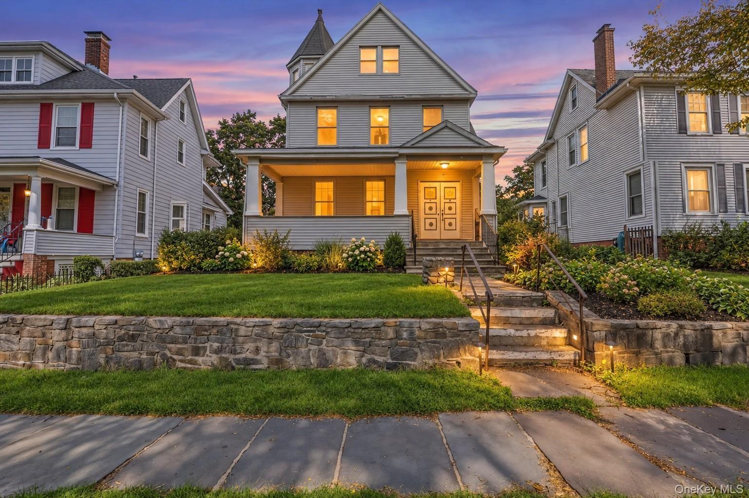 **Virtually Staged** Stately multi-story residence featuring a covered front porch, prominent dormer, and a stone retaining wall