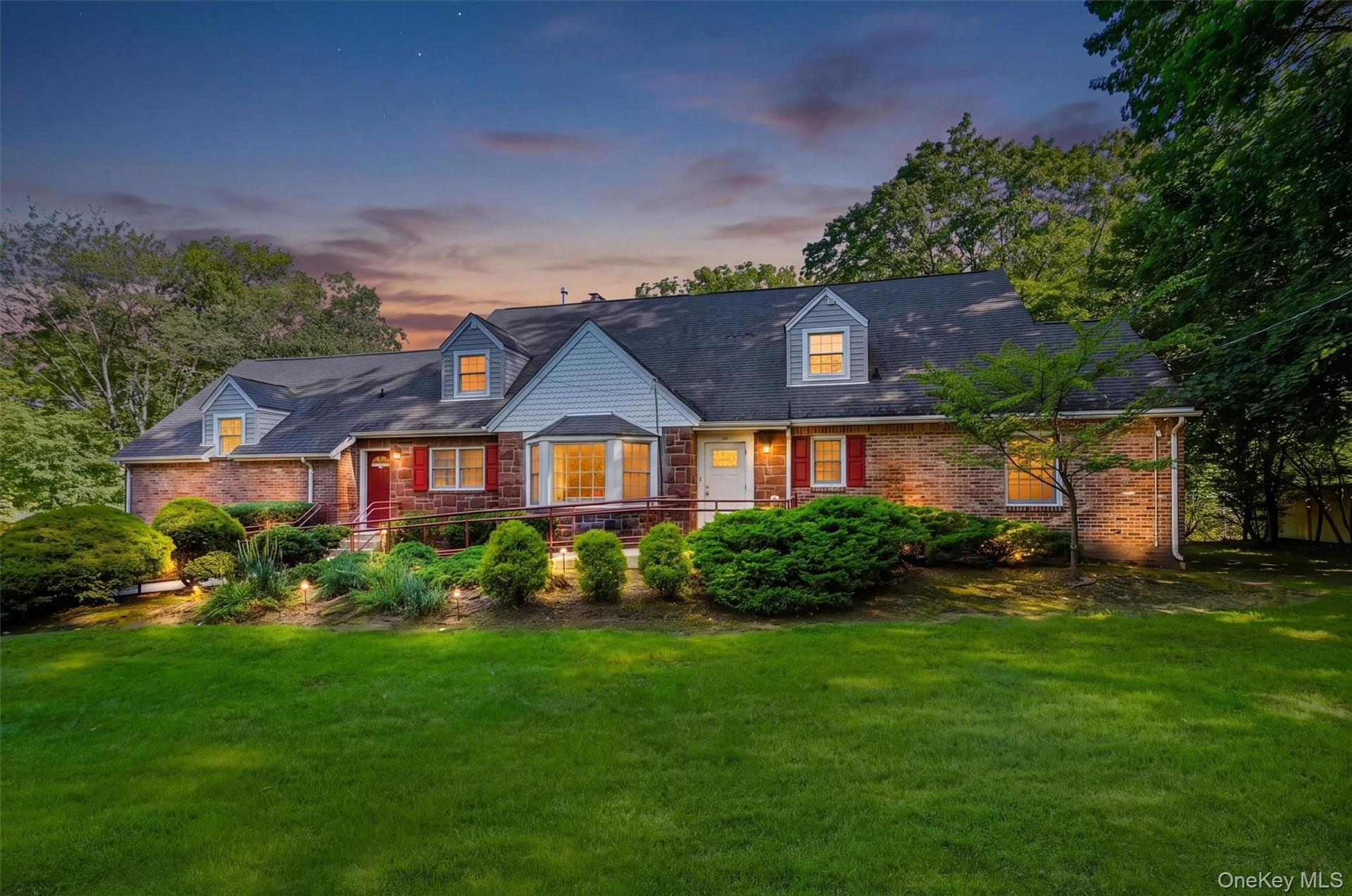 Impressive brick-and-stone professional building surrounded by mature landscaping and illuminated for a welcoming evening presentation.