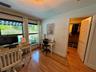 Bedroom featuring wood-finish flooring, plantation shutters, and a ceiling fan with integrated lighting