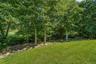 Expansive green lawn with a natural stone retaining wall and mature trees
