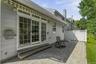 Paved patio with white privacy fencing, sliding glass doors with transom windows, and a retractable awning