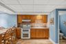 Kitchenette featuring wood-finish cabinetry, a ceramic tile backsplash, and a double oven range