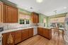 Wood-finish flooring, wood cabinetry, white countertops, tile  backsplash, and recessed lighting