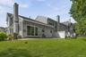 Rear exterior featuring a large patio, extensive lawn, and white privacy fencing