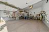 Spacious garage with speckled epoxy flooring, overhead door openers, built-in shelving, and a raised storage platform with staircase access