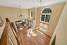 Two-story foyer featuring wood-finish flooring, a tiered window arrangement with an arched transom, an ornate chandelier, and a ceiling fan