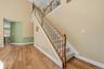 Two-story foyer with vaulted ceilings, wood-finish flooring, and a staircase featuring carpeted treads and wood handrails