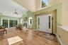 Vaulted ceiling with recessed lighting, wood-finish flooring, white  fireplace, multiple large windows, and a front entry door with sidelights