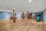 Wood-finish flooring, recessed lighting, drop ceiling, light blue walls, and a visible staircase