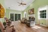 Vaulted ceiling with a ceiling fan and recessed lighting, wood-finish  flooring, a white fireplace mantel, and sliding glass doors