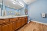 Double vanity with wood-finish cabinetry, white countertop, and dual sinks
