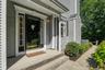 Paneled front door with sidelight windows, covered entry, concrete  steps, horizontal siding, and a paver walkway