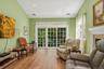 Wood-finish flooring throughout, recessed ceiling  lighting, a fireplace with a white mantel, and a sliding glass door with transom windows