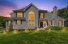 VIRTUAL STAGING Gray siding exterior with black shutters, prominent arched window, stone accent column, front entry with transom window, and establish