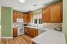 U-shaped kitchen featuring wood-finish cabinetry, white appliances, a double basin sink, and wood-finish flooring